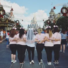 a group of women in pink shirts and black pants standing next to each other on a street