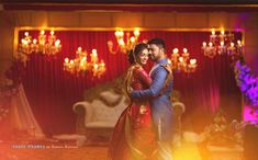 a man and woman dance together in front of a stage with chandelier lights