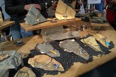 people are looking at various types of items on display in a museum exhibit area with wooden boards and metal objects