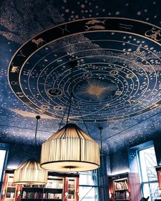 the ceiling is decorated with stars and moon designs on it, while two lamps hang from them