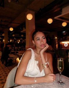 a woman sitting at a table with a glass of wine in front of her face