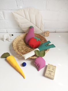 a basket filled with stuffed vegetables next to a toy carrot and some other toys on a table