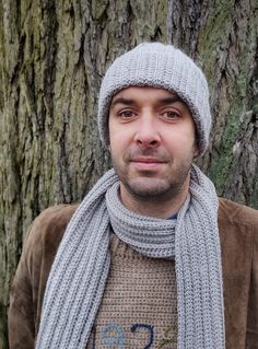 a man wearing a hat and scarf next to a tree