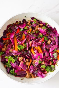 a white bowl filled with red cabbage and meat