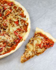 a pizza sitting on top of a table next to a slice of pizza