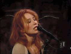 a woman with red hair singing into a microphone