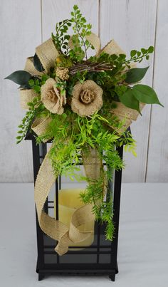 a vase filled with flowers and greenery next to a candle