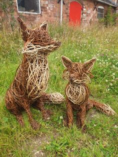 two sculptures made out of twigs sitting in the grass