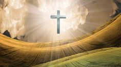 a cross in the middle of a field with clouds and sunbeams behind it