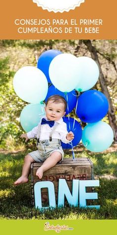 a little boy sitting on top of a crate holding blue and white balloons with the word one above it