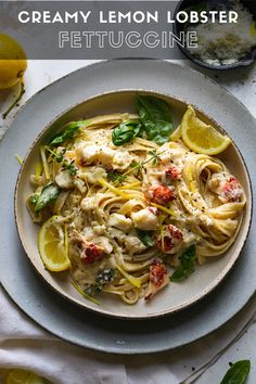 creamy lemon lobster fettuccine on a plate with lemon wedges and basil