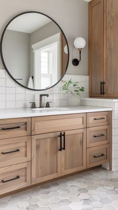 a bathroom with wooden cabinets and a round mirror