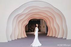 a woman standing in front of a white and pink tunnel