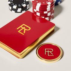 a red playing card next to poker chips and a gold plate with the letter r on it