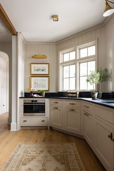 a kitchen with white cabinets and black counter tops next to a rug on the floor