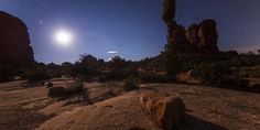 the moon shines brightly in the sky above some rocks