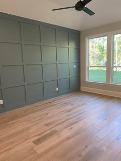 an empty room with wood floors and large windows in the center is painted blue gray