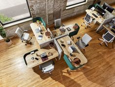 an overhead view of office desks with computers and laptops on them, in the middle of a wood floored room