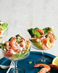 shrimp salad with lettuce and tomatoes in small glass dishes on a blue tray