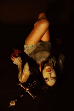 a woman laying on the ground with her face painted white and holding a knife in one hand