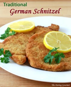 fried fish with parsley and lemon slices on a white plate