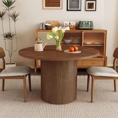 a dining room table with two chairs and a vase on the table next to it