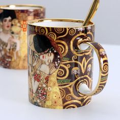 two coffee mugs one with a gold handle and the other has an image of a woman on it