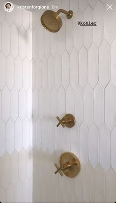 two gold faucets in the shower with white tile and hexagonal tiles