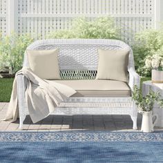 a white couch sitting on top of a blue rug next to a wooden table and potted plant