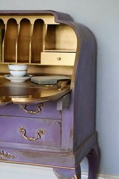 an old purple dresser with dishes on it