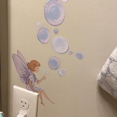 a bathroom wall decorated with bubbles and a fairy sitting on it's back end