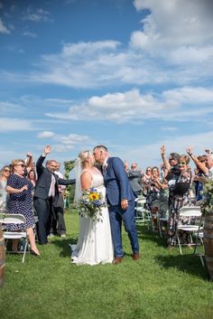 a bride and groom kiss as they walk down the aisle after their wedding ceremony at an outdoor venue