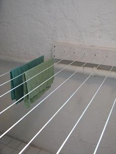 two towels hanging on a clothes line in a room with white walls and tile flooring