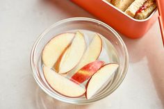 sliced apples in a glass bowl next to an orange container with two pieces of cake