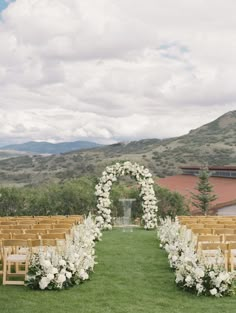 an outdoor ceremony setup with white flowers and greenery