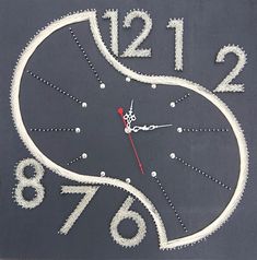 a clock made out of white thread on a gray surface