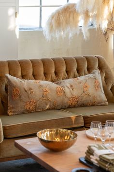 a brown couch sitting next to a table with plates and glasses on top of it