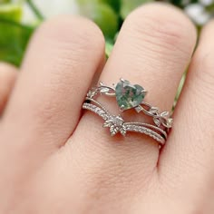 a woman's hand holding a ring with an aqua green stone and white diamonds