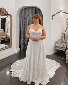 a woman standing in front of a mirror wearing a wedding dress