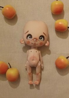 an odd looking doll is surrounded by apples and oranges on the wall, with one face partially covered in fake flesh