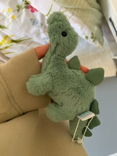 a green stuffed animal sitting on top of a bed