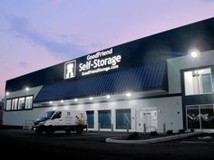 the front of a self storage building at night with two trucks parked in front of it