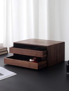 an open drawer on top of a desk next to a pen and ink rollers