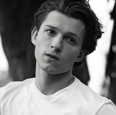 a young man in a white t - shirt poses for the camera