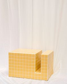 two pieces of yellow tile sitting next to each other on a white sheeted surface