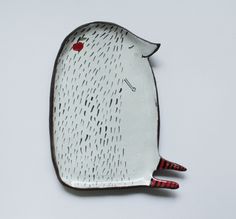 a white plate with an animal design on it's side and red feet is shown in the shape of a fish