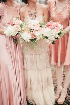 three bridesmaids in pink dresses standing next to each other and holding bouquets