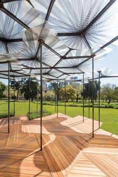 an outdoor area with wooden benches and umbrellas on the ground in front of trees