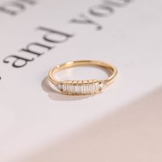 a gold ring with three baguettes on it sitting on top of a piece of paper