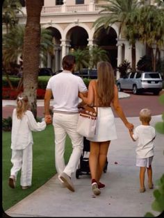 a family walking down the sidewalk holding hands